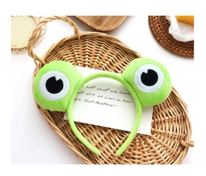 Gros plan d'un serre-tête en peluche aux yeux de grenouille dans un panier de style rustique