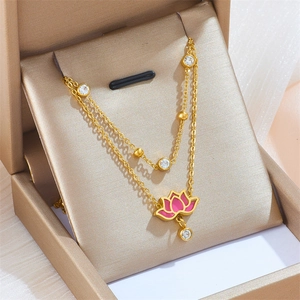 Detailed close-up of double-layer necklace with pink enamel lotus in a golden gift box