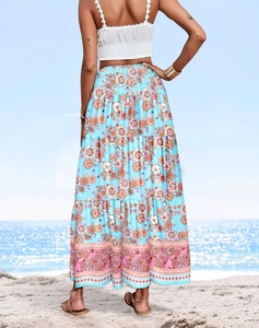 Back view of bohemian sky blue high-waist maxi skirt with orange floral prints on a beach