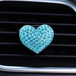 Close-up of heart-shaped car air vent clip with sparkling blue rhinestones