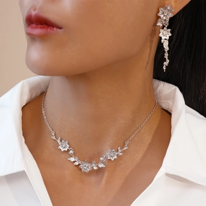Gros plan d'un ensemble collier et boucles d'oreilles argentés à motifs floraux