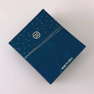 Premium dark blue jewelry gift box with gold dots and a handmade label on a grey table
