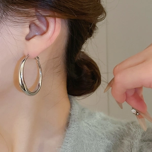 Polished silver C-shaped hoop earrings on model showing size and metallic luster