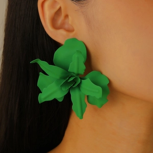 Close-up of oversized green 3D floral earrings featuring textured layered petals on model
