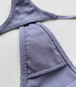 Detailed macro view of purple ribbed cotton fabric and fine stitching on thong underwear