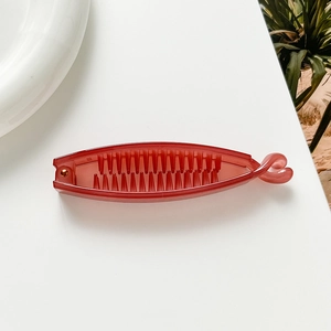 Detail shot of a red plastic banana hair clip with secure twist lock on white background