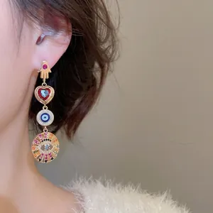 Bohemian gold-plated earrings with Fatima hand heart and evil eye charms on model