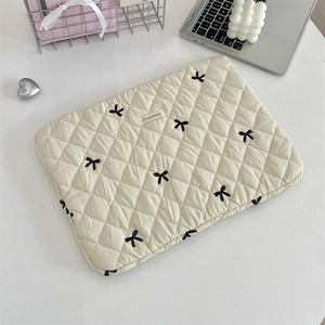 Detailed embroidery of rabbit bows on quilted cream-colored laptop sleeve