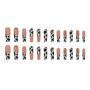 Cow print press-on nails with gold lines and rhinestones in long coffin shape
