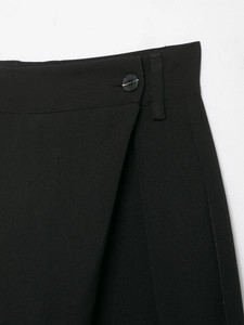 Detail of black trousers featuring a double button closure and twill fabric texture