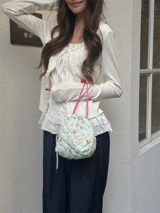 Detail of mint green quilted drawstring pouch with floral cartoon patterns and woven handles