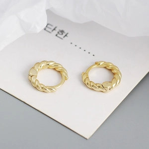 Close-up of golden twist rope hoop earrings with soft metallic luster on white background