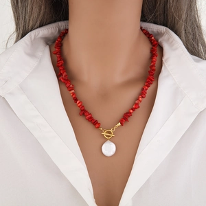 Detail of beaded necklace with red stones, gold toggle clasp and baroque pearl pendant
