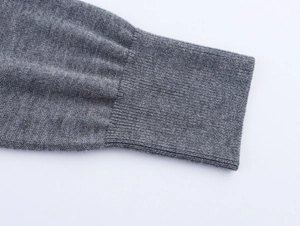 Détail du poignet d'un pull gris en maille présentant une texture côtelée élastique