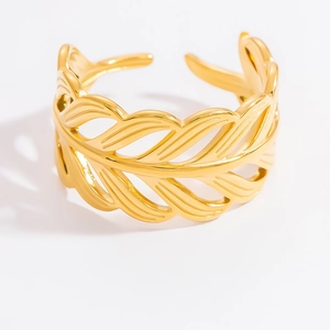 Detailed macro shot of a golden hollow feather pattern on a stainless steel open ring