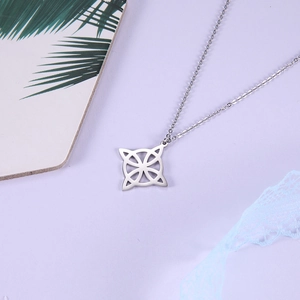 Detailed close-up of a silver Celtic knot pendant on a cross chain over a purple surface