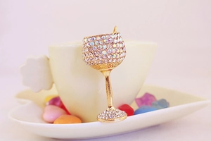 Detailed macro view of rhinestone-encrusted wine glass brooch pin in a warm setting