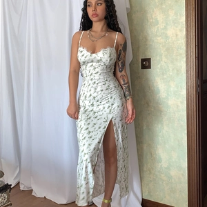 Detail view of lace trim and side slit on a white floral print midi camisole dress