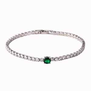 Macro detail of tennis bracelet with square zircons and center green round stone