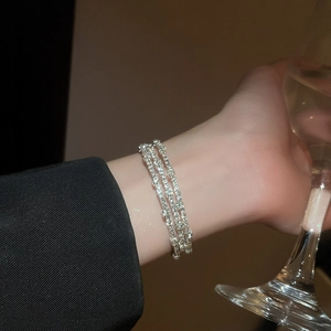 Dettaglio dell'elegante bracciale elastico a tre file di strass con perle argentate
