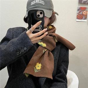 Knitted brown scarf with yellow flower patterns paired with a grey coat and baseball cap