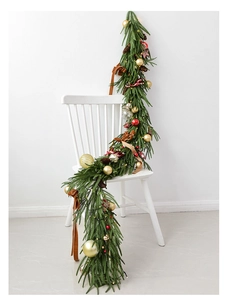 Close-up of Norfolk pine garland with LED lights, festive red balls and pine cones