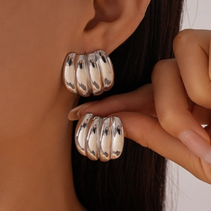 Detail view of silver domed chunky earrings with polished ridge texture for women
