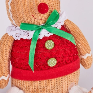 Close-up of gingerbread gnome doll with brown knit fabric and red festive vest detail