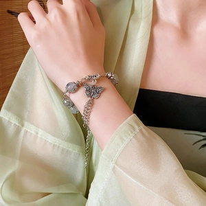 Détail d'un bracelet papillon en argent avec perles de verre grises et pompons en métal