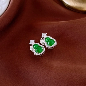 Detail of green jade gourd earrings with sparkling zircon borders on brown silk fabric