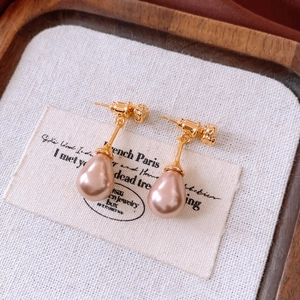 Dettaglio degli orecchini vintage con perle a goccia e finitura in metallo dorato