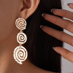 Gros plan de boucles d'oreilles pendantes dorées à trois disques martelés sur mannequin