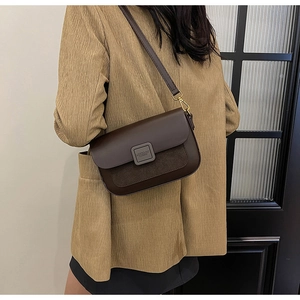 Detail of coffee brown PU leather crossbody bag worn by model over a grey blazer
