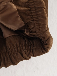 Détail de la taille élastique marron avec coutures précises et doublure soyeuse de veste