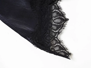 Detailed close-up of smooth black satin fabric stitched with delicate eyelash lace trim