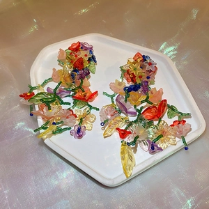 Dettaglio degli orecchini a fiori con perline colorate fatti a mano su vassoio bianco