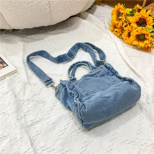 Detailed view of a blue denim handbag with adjustable straps in a lifestyle setting