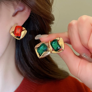 Detail view of vintage gold-plated geometric earrings with red and green crystals