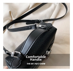 Detail showing black crocodile texture leather and silver metal hardware of the handbag