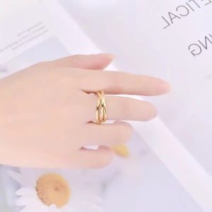 Detail of interlocking gold spinner rings on hand with daisy background aesthetic