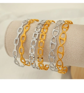 Detailed close-up of Cuban link bracelets in gold and silver on a jewelry display stand
