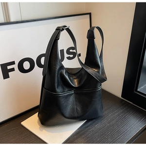 Detailed view of black leather bucket bag showing rich texture on a minimalist setup