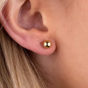 Elegance 18K gold plated stainless steel ball drop earrings worn on model's ear