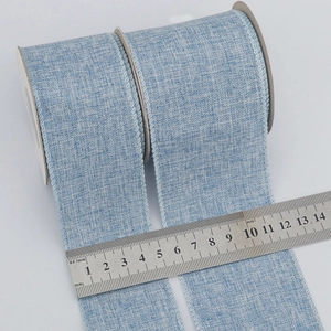 Blue faux burlap Christmas ribbon with 63mm width shown on measuring scale