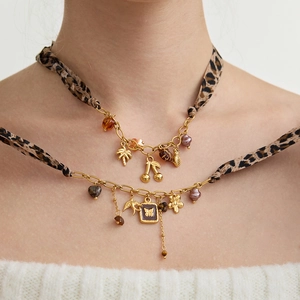 Collier doré multi-rangs avec ruban léopard et breloques tropicales sur modèle