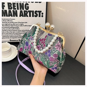 Detail einer floralen Stoffhandtasche mit Retro-Metallverschluss und Doppelperlengriff