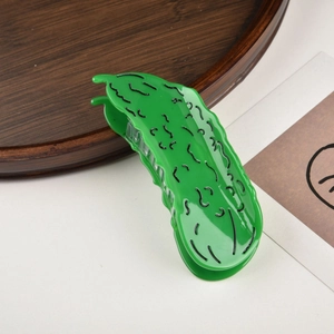 Detailed view of cucumber-shaped hair claw clip with lifelike texture on a tray