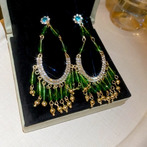 Détail des boucles d'oreilles bohèmes avec perles émeraude et strass brillants en gros plan