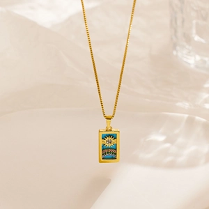 Detail of gold tarot card pendant with blue stone and colorful crystal embellishments