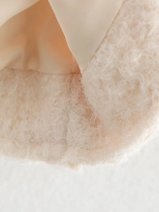 Close-up of beige plush faux fur fabric texture and smooth satin lining on cardigan jacket